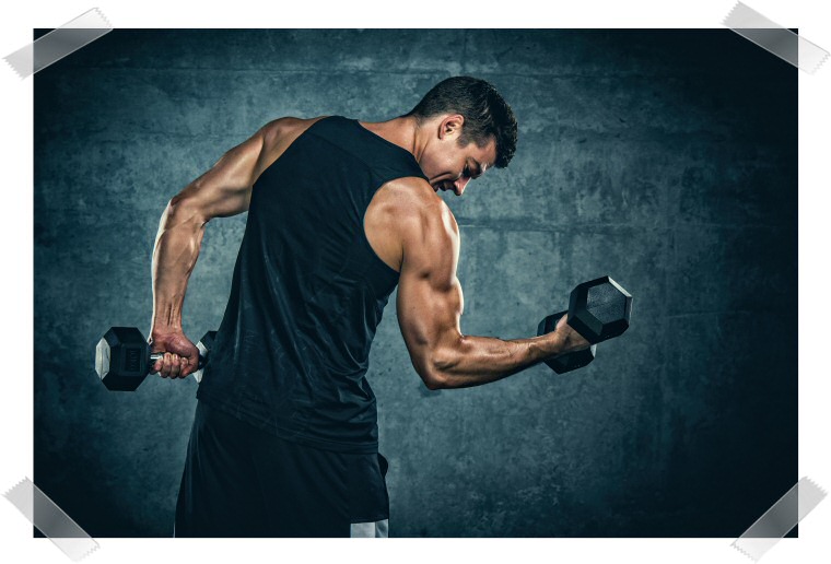A photograph of a muscular man lifting dumbbels one at a time.